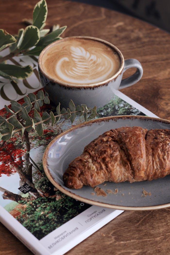 Inviting morning scene with a latte and croissant on a wooden table, perfect for a cozy breakfast.