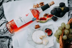 A sophisticated picnic arrangement featuring rosé wine, cheese, figs, and walnuts.