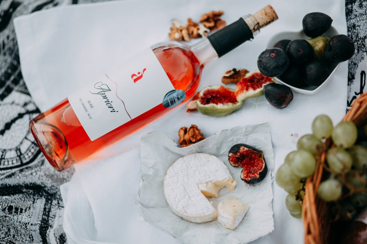 A sophisticated picnic arrangement featuring rosé wine, cheese, figs, and walnuts.